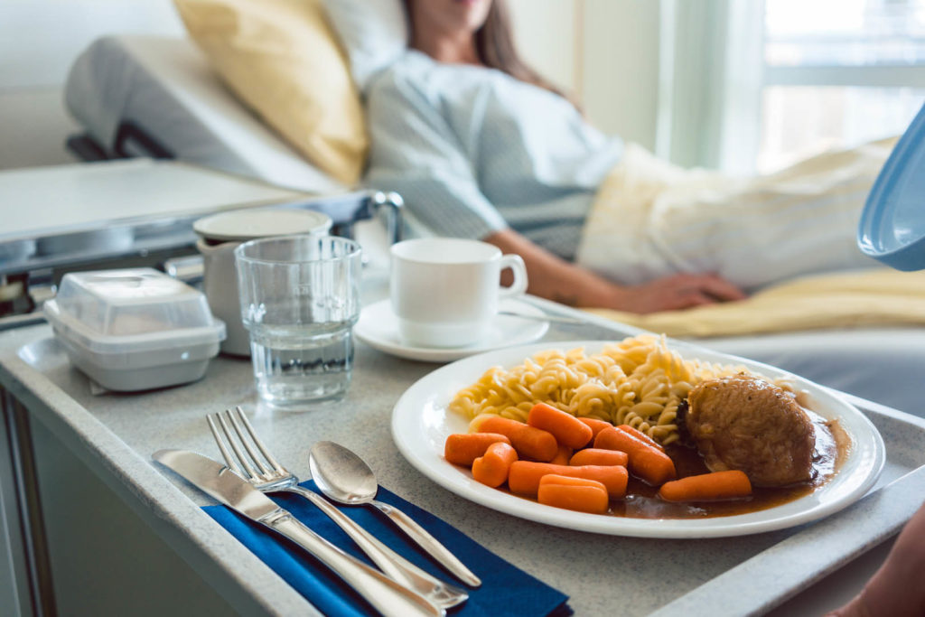 Food delivered to a patient in hospital bed, focus on the meal
